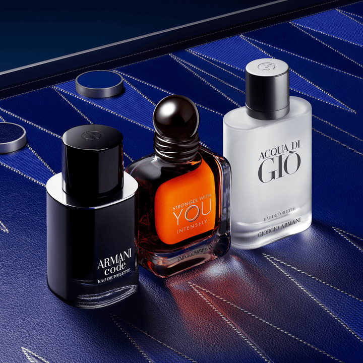 Un trio sofisticato di icone maschili Armani: Armani Code, Stronger With You Powerfully e Acqua di Gio. I flaconi su uno sfondo in pelle blu profondo con motivi geometrici couture, che incarnano un'eleganza maschile assoluta.