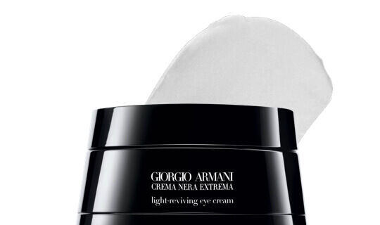 Un frasco de crema para ojos de Giorgio Armani, con una tapa negra y una pequena porcion de crema blanca visible en la parte superior.