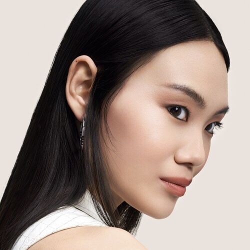 Retrato de una mujer con cabello lacio y piel radiante, mirando de perfil sobre un fondo neutro.