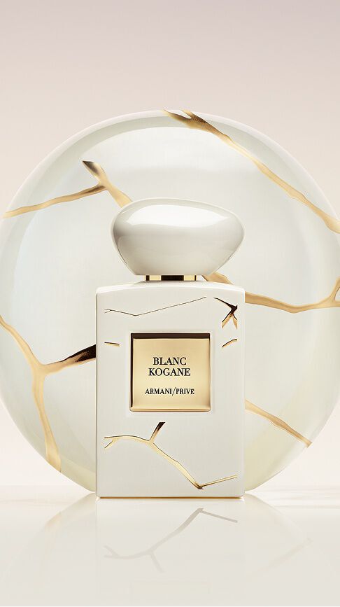 Armani/Prive Blanc Kogane: un frasco blanco puro con veteado dorado, frente a un plato de porcelana Kintsugi, simbolizando una feminidad serena y el resplandor solar del jazmin blanco y el lirio.