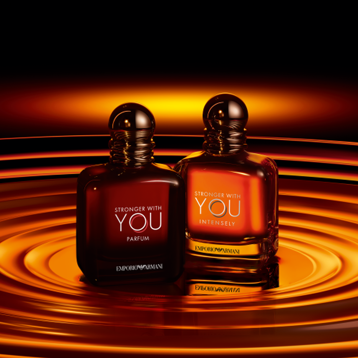 Frascos Emporio Armani Stronger With You Parfum y Stronger With You Intensely, tonos ambar calidos sobre fondo de ondas doradas en espiral