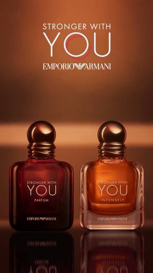 Two stylish perfume bottles from Emporio Armani's 'Stronger With You' collection, one dark and one golden, against a warm background.