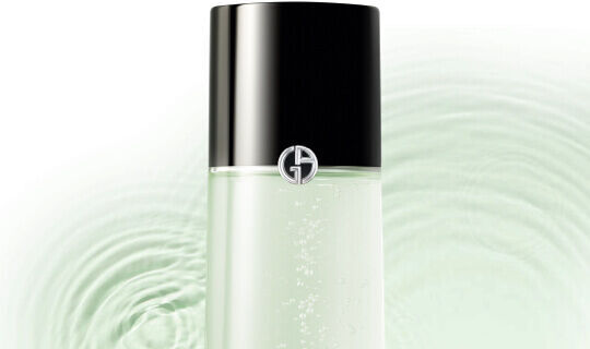 Botella de producto de cuidado de la piel con un diseno elegante, frente a un fondo de ondas de agua verde.