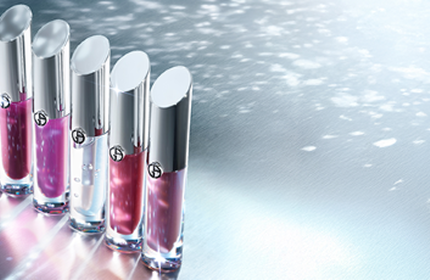 A woman with a sleek ponytail poses gracefully, showcasing her makeup. Next to her is a close-up of two lipstick tubes in red and nude shades.