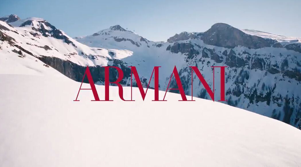 Cinematic Giorgio Armani winter holiday video featuring Madisin Rian and Xavier Serrano in a snowy alpine resort setting, showcasing luxury Armani Beauty gift sets and fragrances like Emporio Armani amidst scenic mountain landscapes.