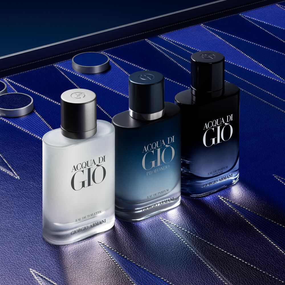 Three Armani Acqua di Gio bottles displayed on a textured blue Blackgammon surface, highlighting the gradient design and the brand’s aquatic, modern fragrance range.