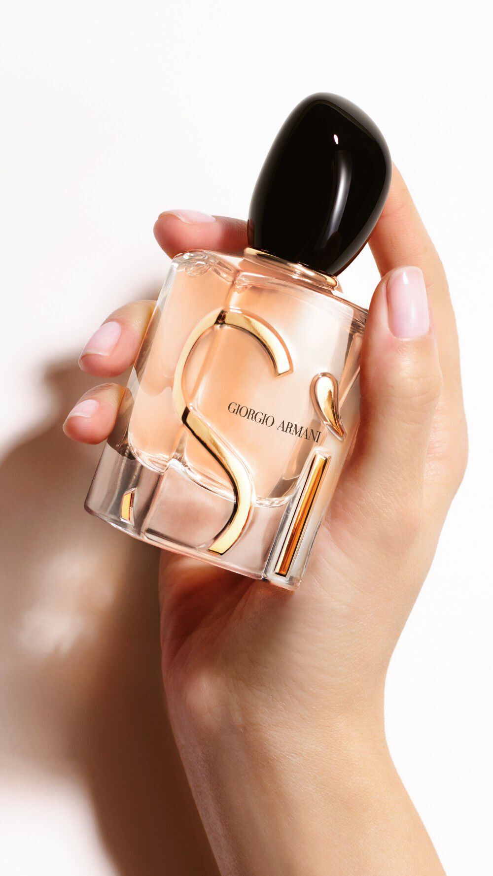 Una mano sosteniendo un frasco de SI EAU DE PARFUM