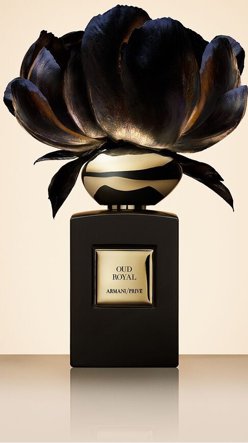 Armani/Prive Oud Royal: un frasco negro profundo coronado por una flor oscura con reflejos dorados, capturando la esencia real de la madera de Oud y el refinamiento sagrado de los palacios orientales.