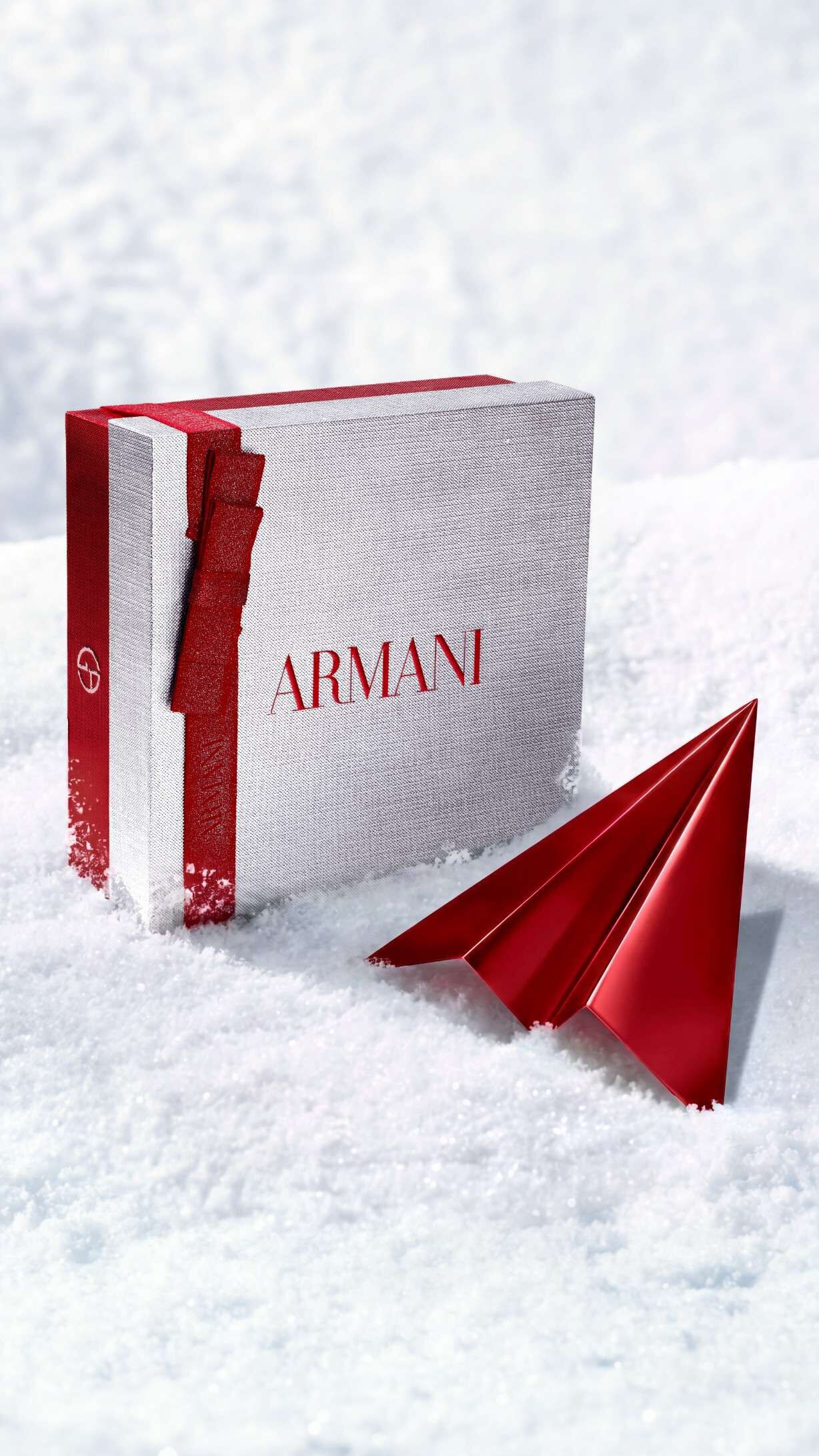 Caja de regalo plateada Armani Beauty con un avion de papel rojo que representa el envio gratuito para las fiestas.