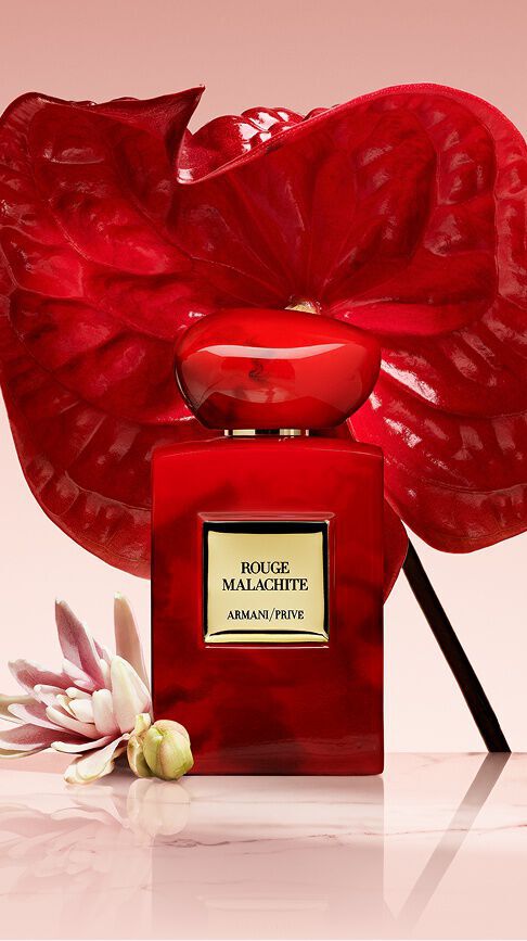 Armani/Prive Rouge Malachite: un apasionado frasco rojo con veteado organico, coronado por una vibrante flor de anturio, simbolizando la energia vibrante y la calidez carnal de la tuberosa.