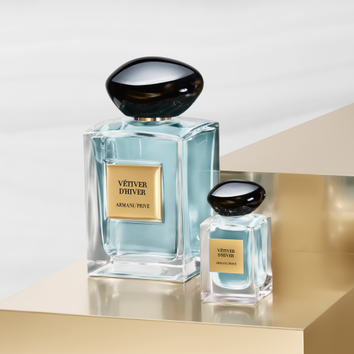 Armani/Prive: un frasco iconico y su elegante miniatura revelando una esencia verde palido. Sobre un pedestal dorado, celebran el equilibrio sereno del te y el lujo artesanal couture de la Casa Armani.