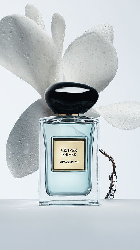 Armani/Prive Vetiver d'Hiver: un frasco con nectar azul claro, rodeado de delicados petalos blancos con rocio matutino, que evoca la frescura viva y luminosa del invierno.