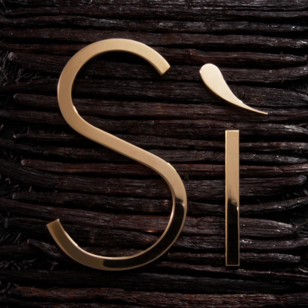 Logo 'Si' en dorado sobre un fondo de texturas oscuras de madera. Elegante y minimalista.