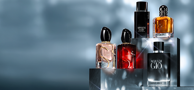 A vibrant display featuring various perfume bottles arranged on white boxes, set against a bold red background. An elegant gold key and a vintage-style phone are included in the composition, enhancing the luxurious theme.