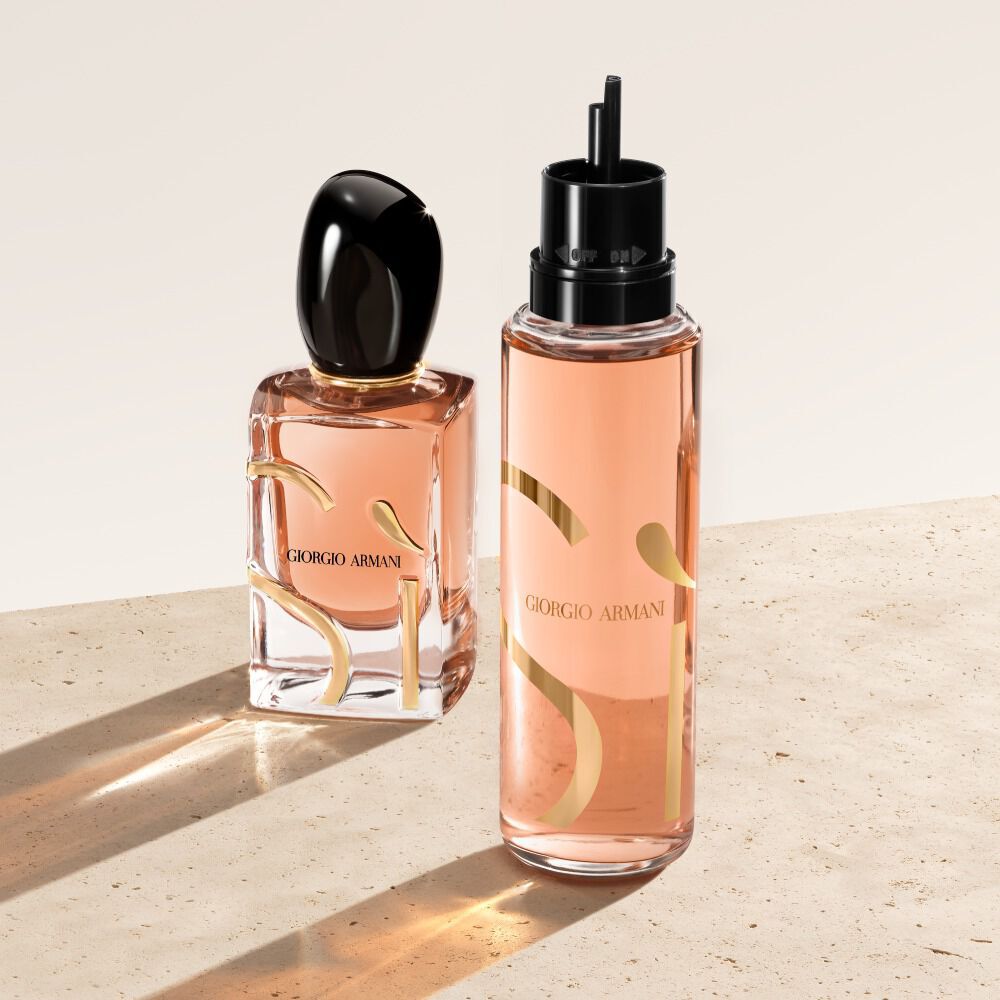 Dos frascos de Eau de Parfum Si de Giorgio Armani sobre una superficie beige. El frasco de la izquierda es el clasico frasco de la fragancia Si, mientras que el de la derecha es un frasco de recarga con una apariencia mas translucida y de tono melocoton.