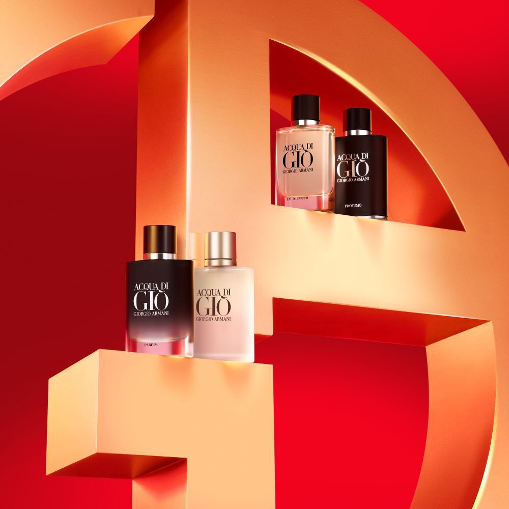 A vibrant display featuring four bottles of Acqua di Gio by Giorgio Armani, arranged against a bold red background and positioned on a large, stylized '4' sculpture.