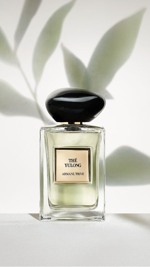 Armani/Prive The Yulong: un frasco con una esencia verde palido, sobre un fondo minimalista de sombras de hojas, que encarna el equilibrio sereno entre el te ahumado y el verde.