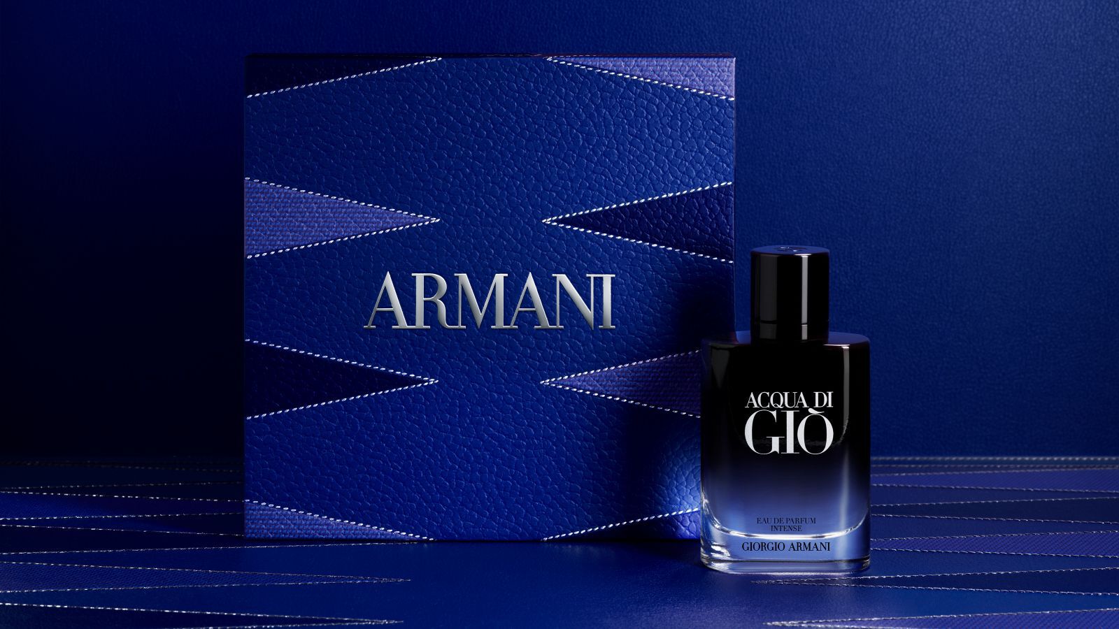Frasco de fragancia Giorgio Armani "Acqua di Gio" con una caja de regalo Armani azul texturizada.