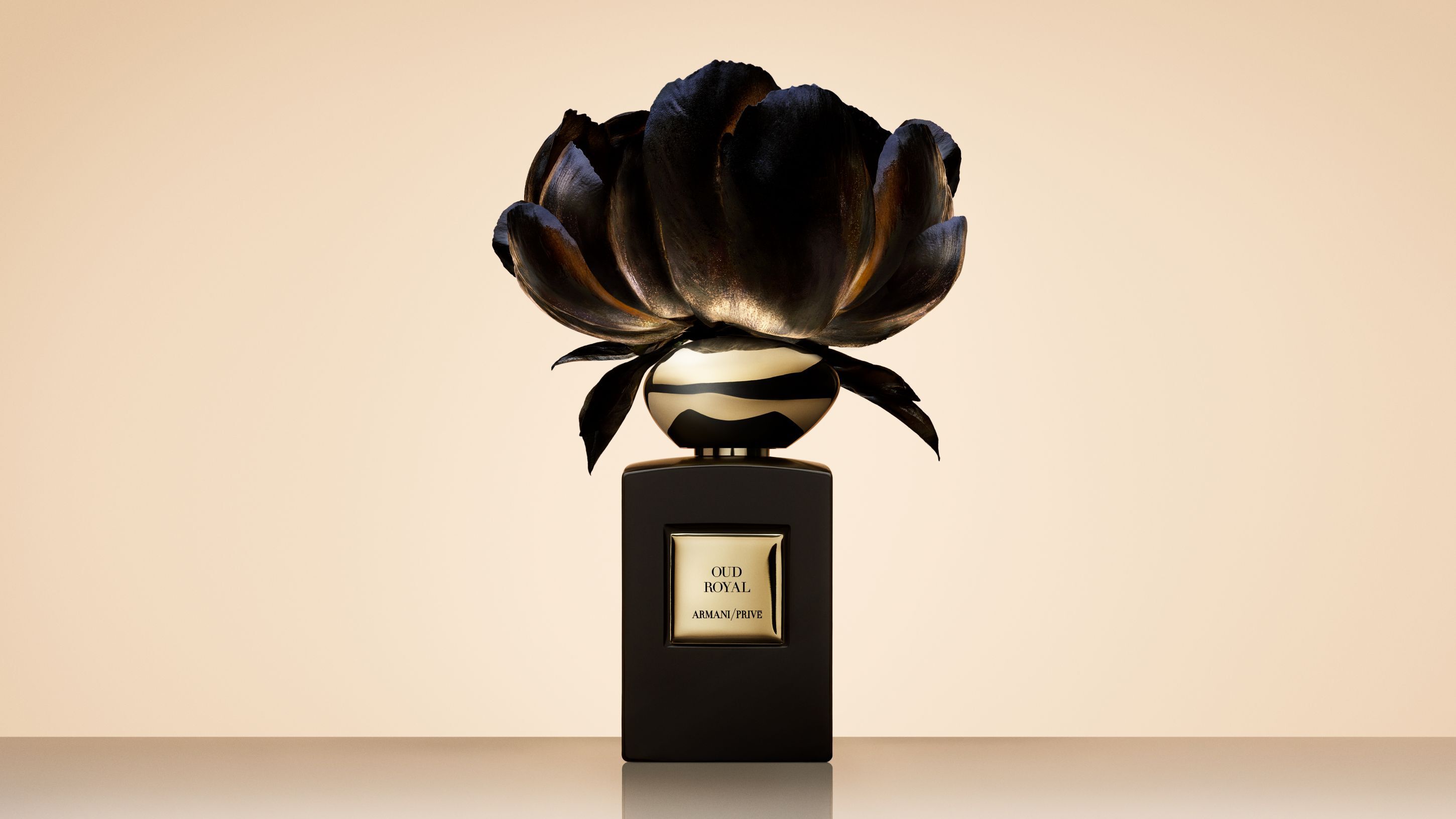 Frasco de perfume Armani/Prive Oud Royal coronado con una gran flor negra artistica.