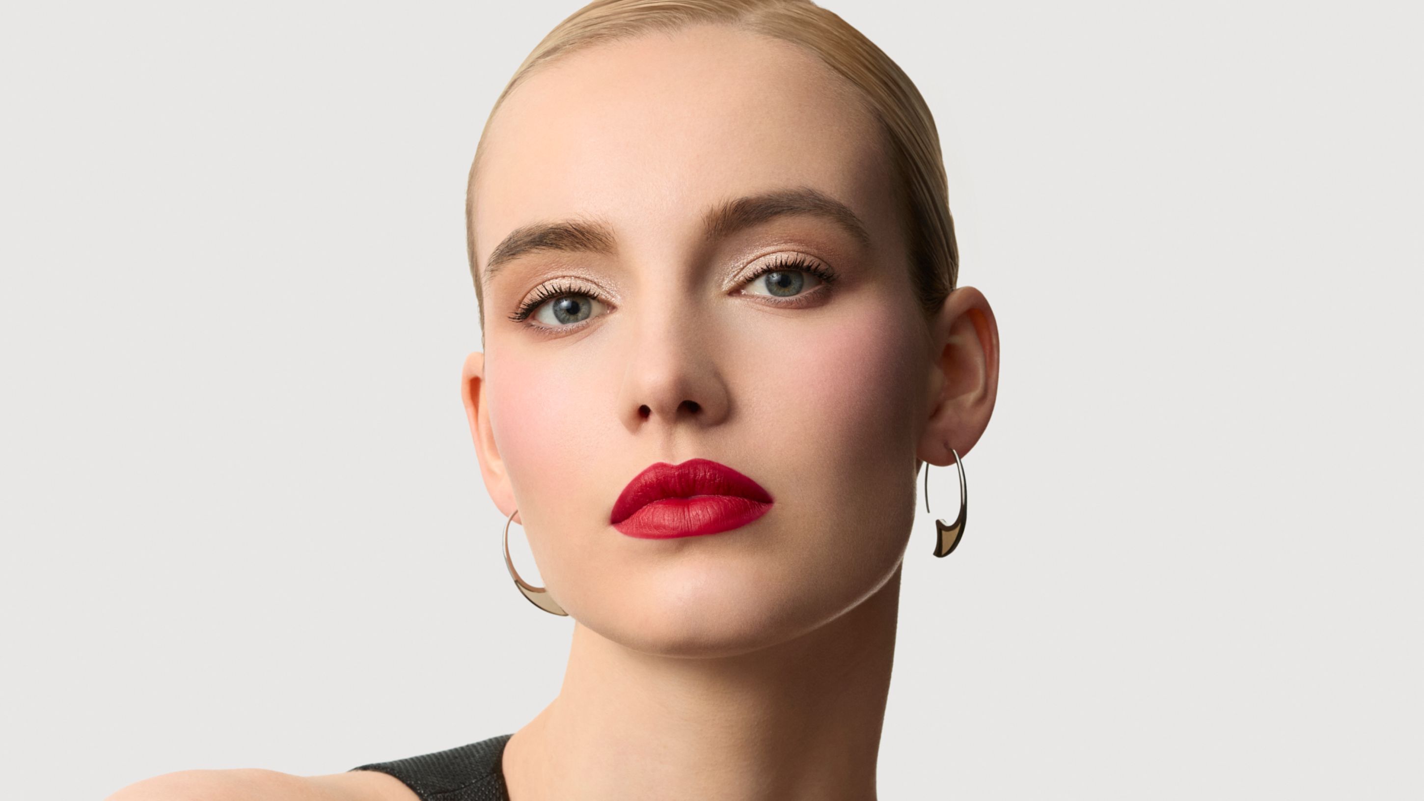 Primer plano de una mujer rubia con maquillaje elegante y labios rojos intensos.