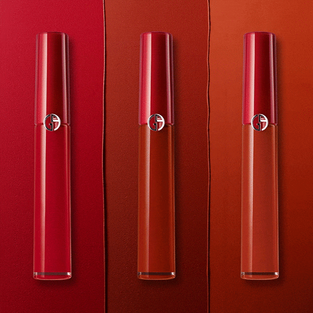 Tres esmaltes de labios de Armani en tonos rojos, sobre un fondo de colores rojo y naranja.