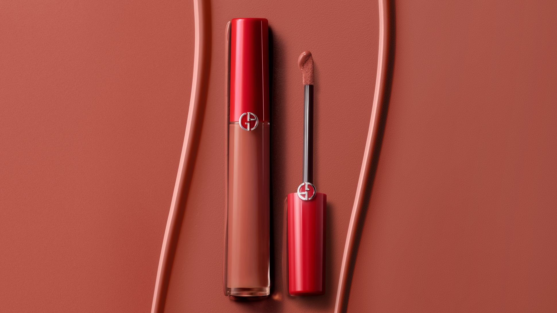 Labial líquido Giorgio Armani con aplicador sobre un fondo terracota texturizado.