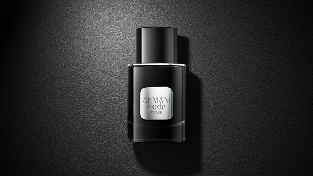 Un frasco negro de perfume Armani Code Elixir descansa elegantemente sobre una superficie negra a juego, creando un sofisticado look monocromo