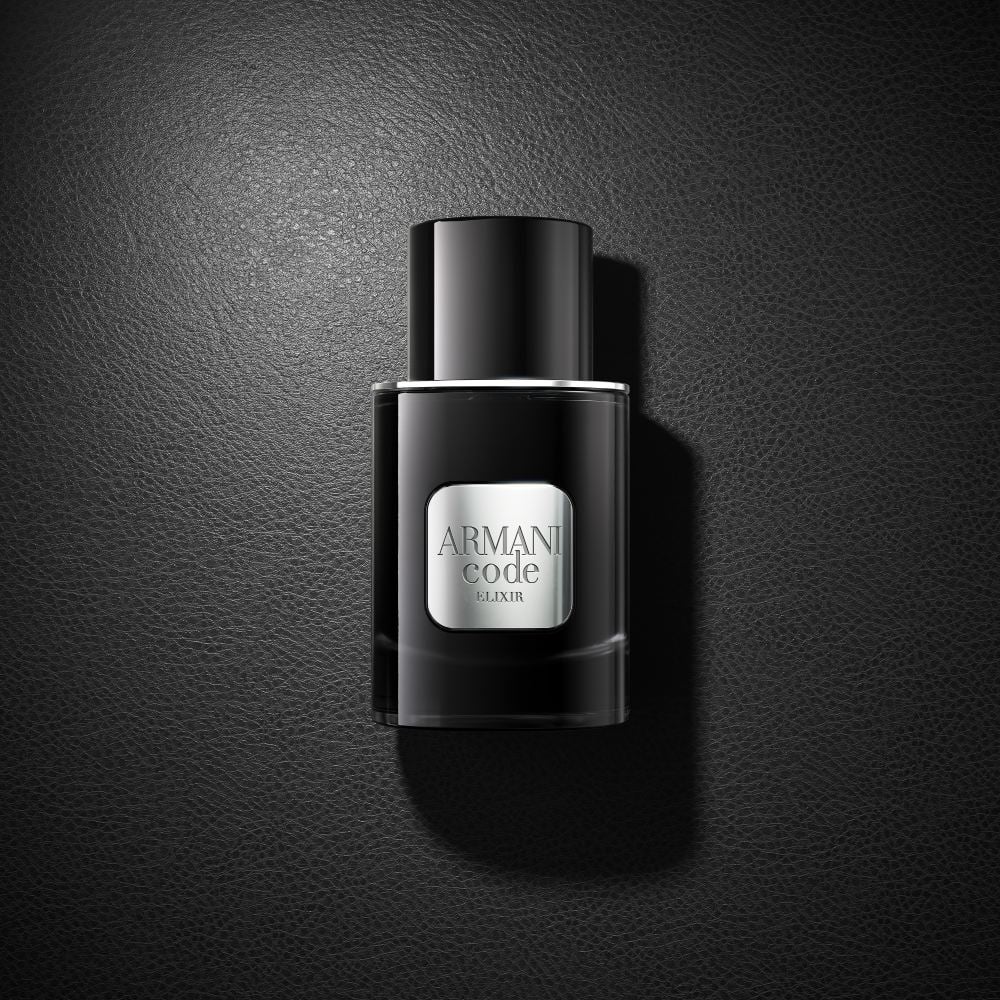 Un frasco negro de perfume Armani Code Elixir descansa elegantemente sobre una superficie negra a juego, creando un sofisticado look monocromo